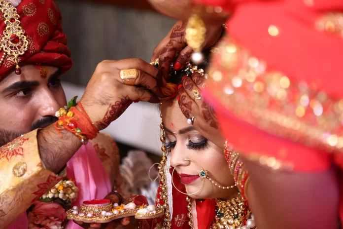 man putting sindoor on woman forehead