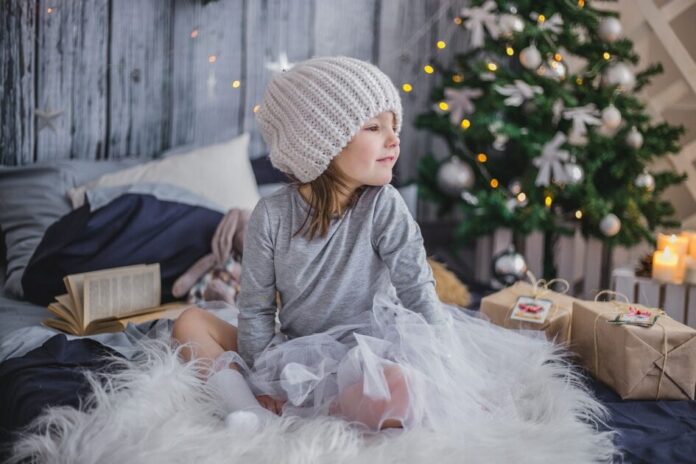 kid smiling happy near a christmas tree